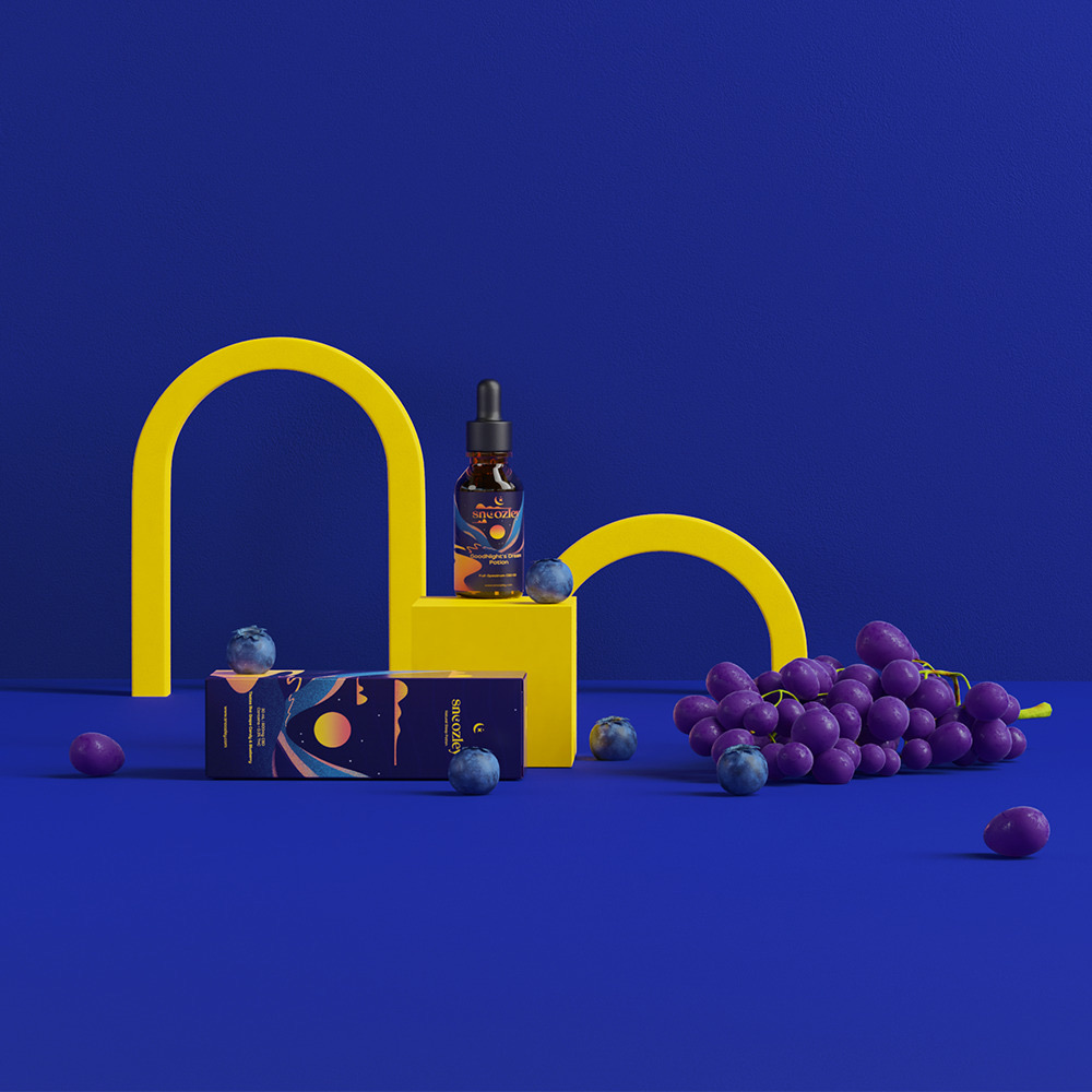 Snoozley bottle and packaging staged with yellow arches and grapes on a deep-blue set