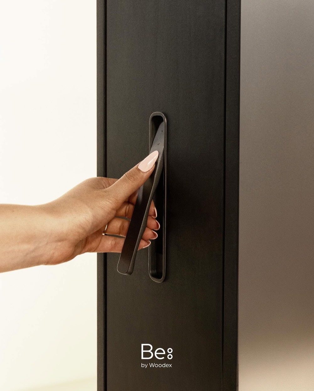 Hand opening a Be by Woodex cabinet by its slim recessed black handle